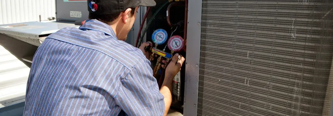 HVAC technician servicing a condenser unit in Hermitage